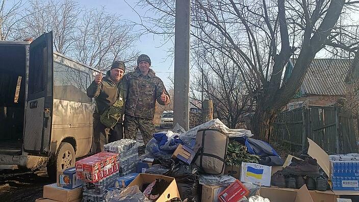 Zwei Soldaten stehen hinter einem Stapel von verschiedenen Hilfsgütern