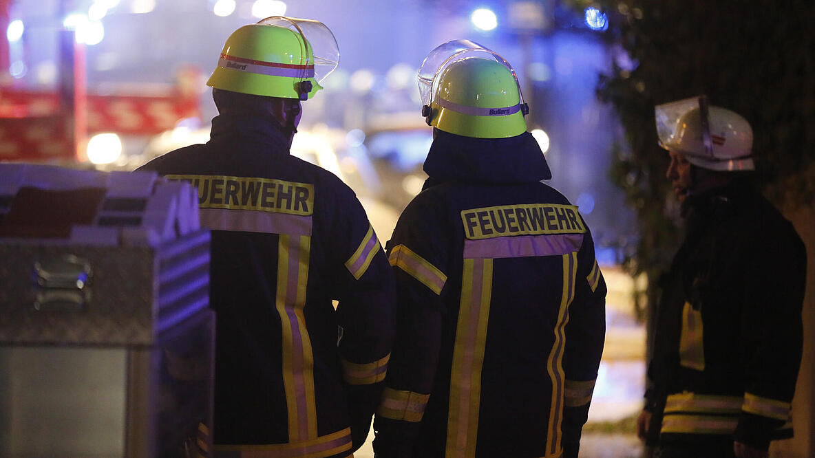 Feuerwehrleute in Schutzkleidung von hinten.